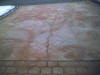 An imprinted concrete driveway laid after only 10 year of normal use - cracks and grey concrete showing through the red terracotta layer